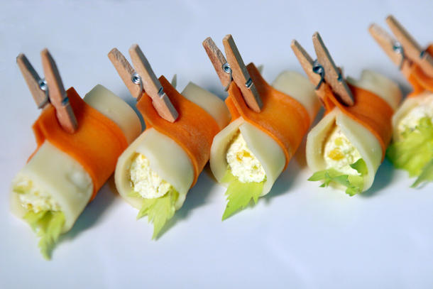 Канапе-рулетик на прищепке из сыра с сливочным муссом и орехами, обёрнутый слайсом морковки